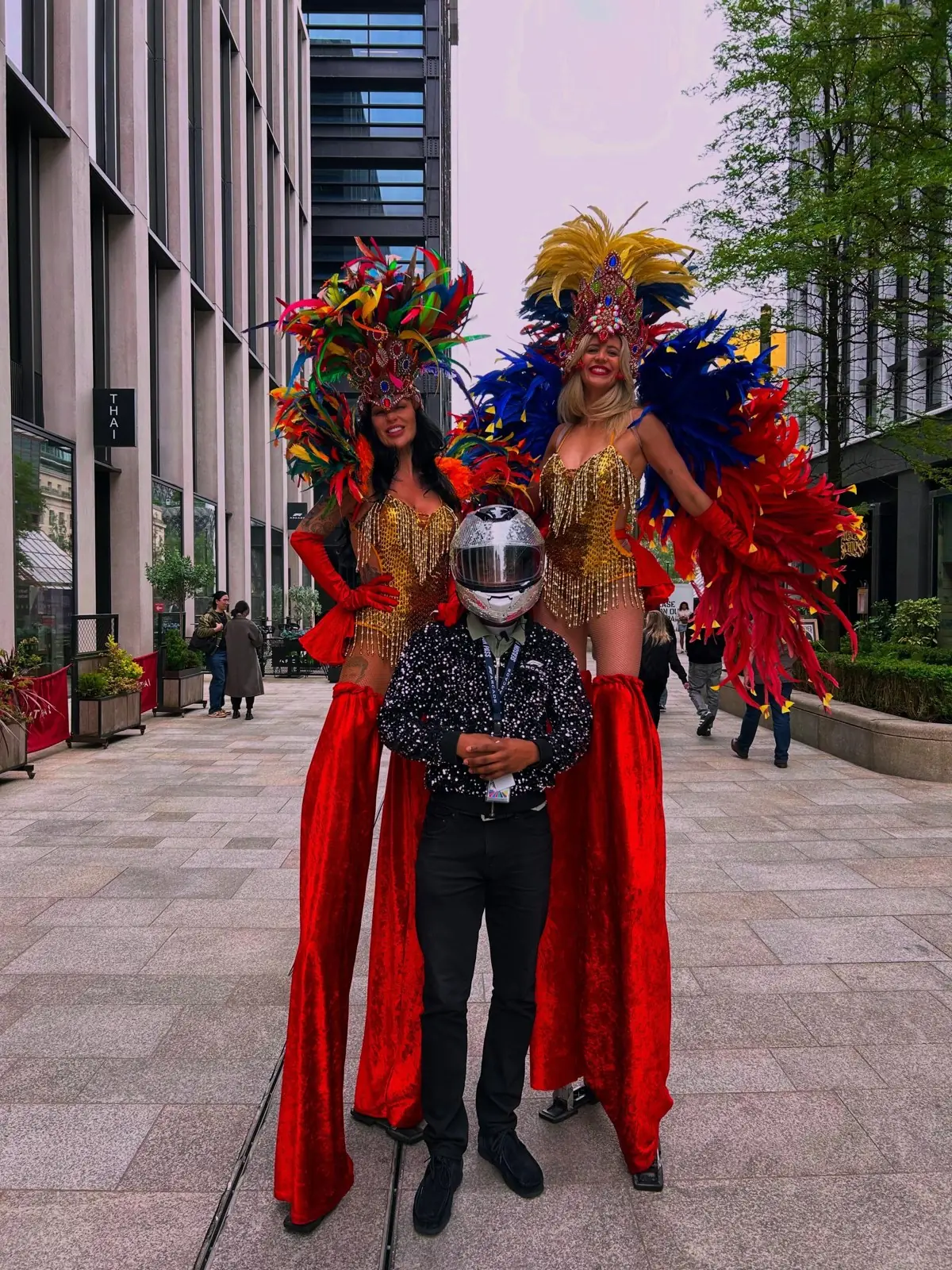 Carnival stilt walkers in red and gold feathers on a city street
